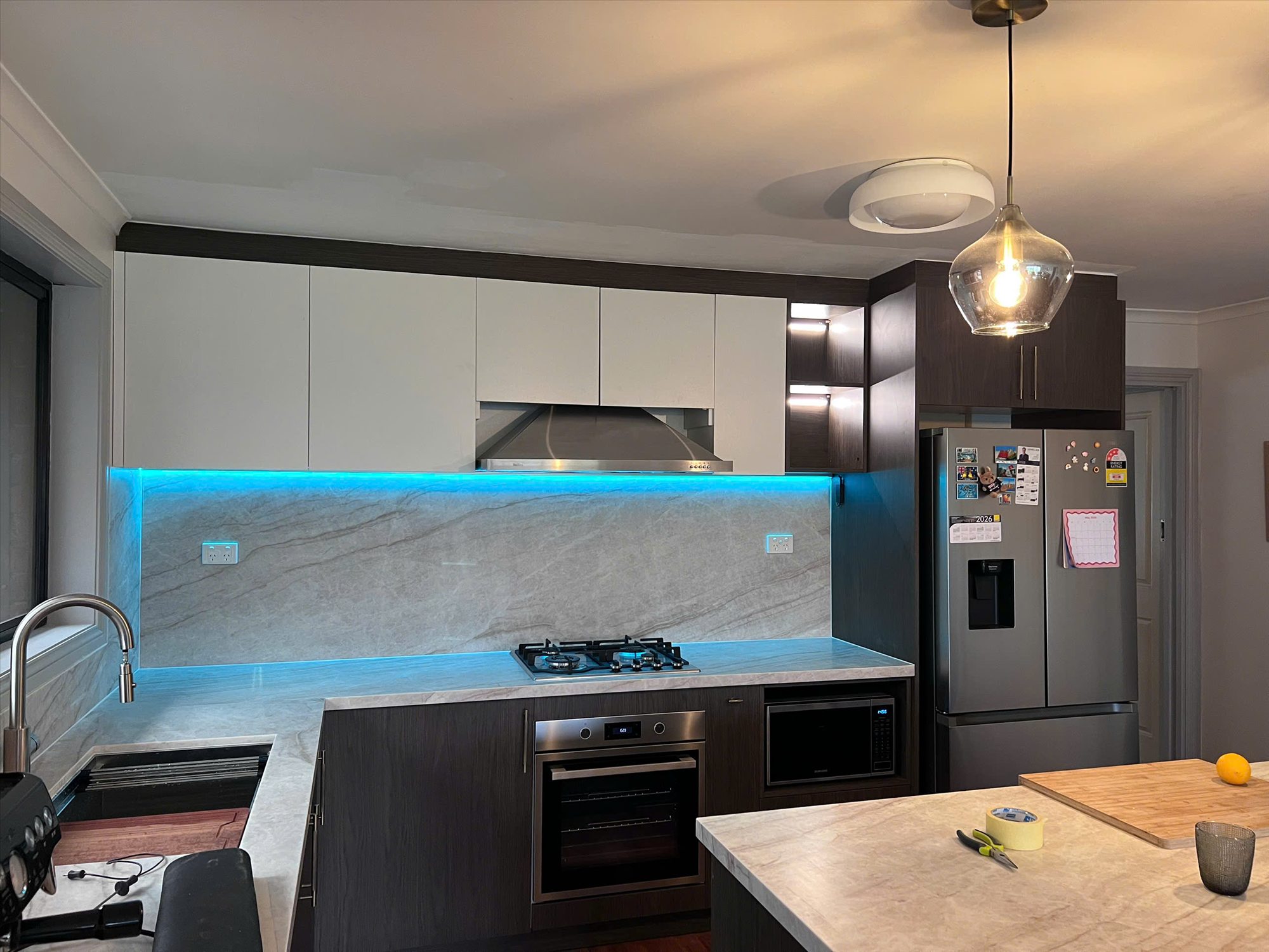 Completed custom kitchen by TL Joinery with dark timber cabinetry and stone-look surfaces